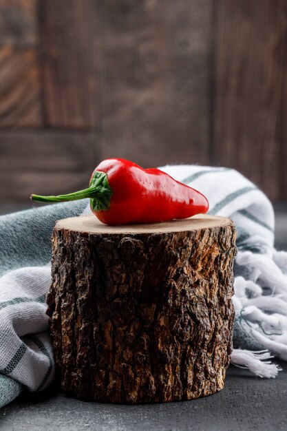 Poivron rouge sur une pièce en bois avec tissu pique-nique vue latérale sur le mur de carreaux gris et pierre