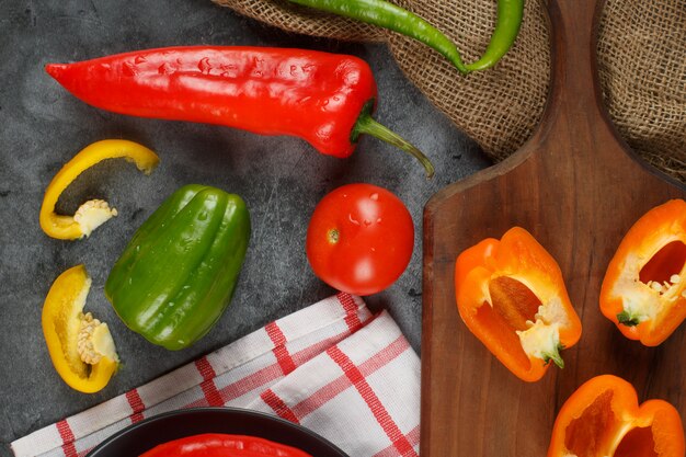 Poivrons colorés sur une planche de bois. Vue de dessus.