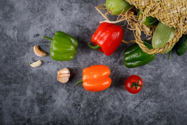 Poivrons de couleur verte, rouge et orange dans un panier rustique.