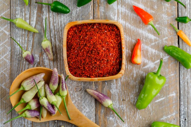 Poivrons avec des flocons de piment rouge dans une cuillère en bois sur bois,