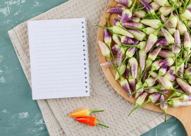 Poivrons sur planche à découper avec ordinateur portable à plat sur du plâtre et un torchon