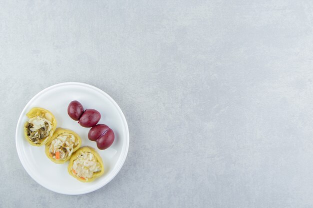 Poivrons et prunes farcis sur plaque blanche.