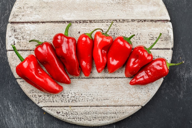 Poivrons rouges dans une pièce en bois sur un mur de grunge sombre. mise à plat.