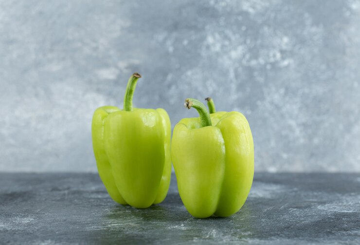 Photo gratuit poivrons verts biologiques sur fond gris.