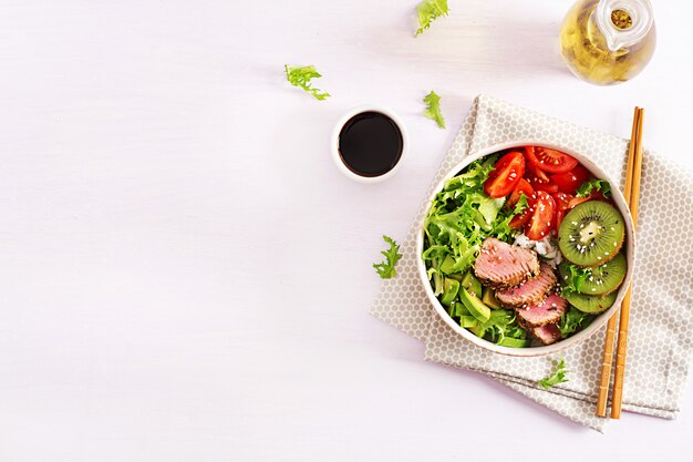 Poke bowl. Bol de Bouddha. Salade traditionnelle avec des morceaux de thon Ahi grillé mi-rare et sésame avec salade de légumes frais et riz sur une assiette