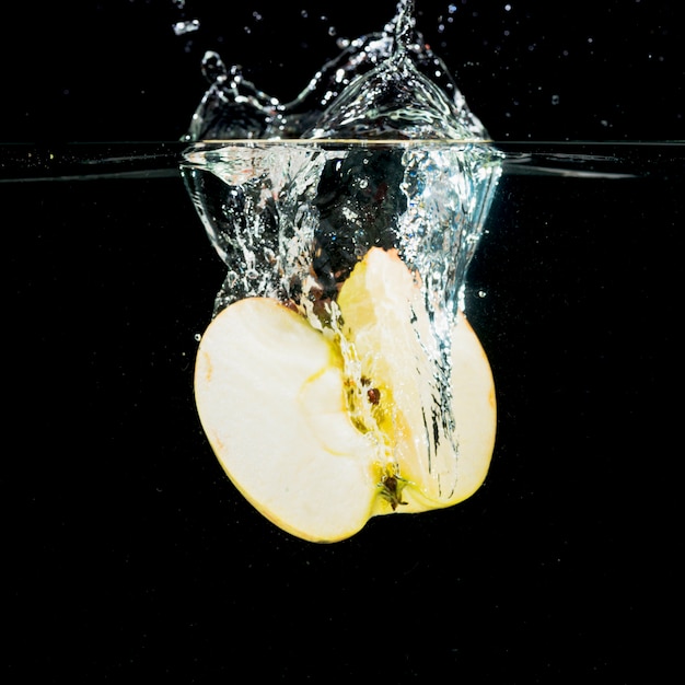 Pomme coupée en deux éclaboussures dans l&#39;eau sur fond noir