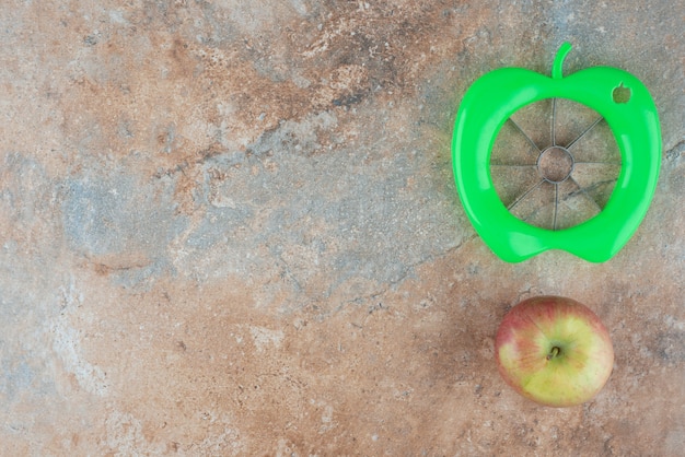 Photo gratuite une pomme douce entière avec outil d'épluchage sur table en marbre.