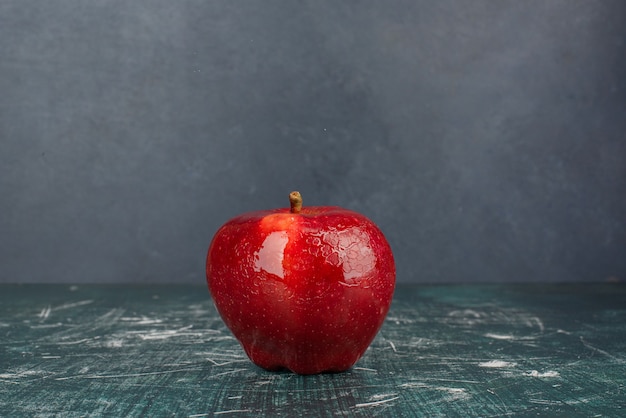 Pomme entière rouge sur fond bleu.