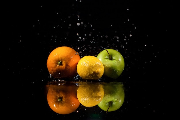 La pomme, l&#39;orange et le citron se tiennent sur le fond noir