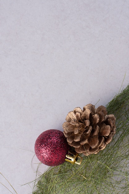 Pomme de pin avec boule de Noël sur une surface blanche