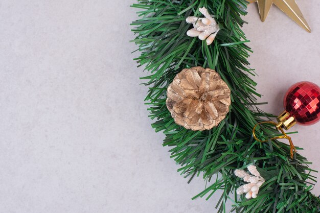 Pomme de pin avec boule de Noël sur une surface blanche