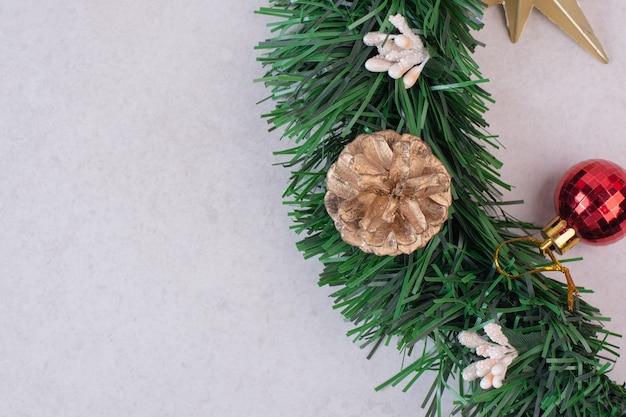 Pomme de pin avec boule de Noël sur une surface blanche