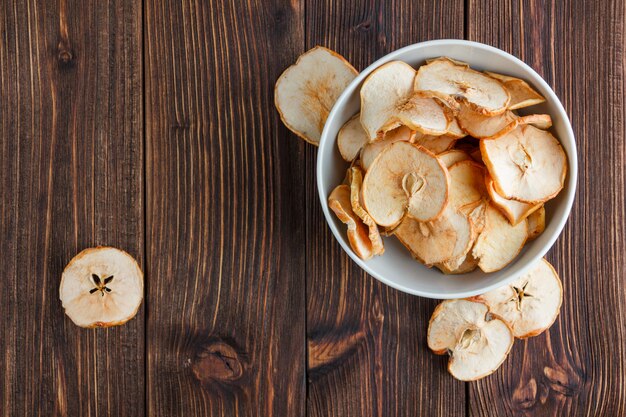 Pomme sèche dans un bol sur un fond en bois. vue de dessus. espace pour le texte