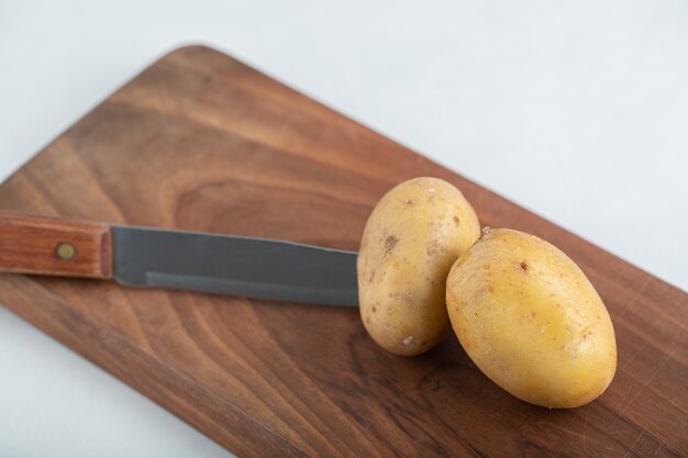 Pomme de terre biologique fraîche et couteau sur planche de bois brun