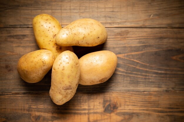 Pomme de terre crue sur fond en bois.