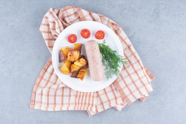 Pomme de terre frite avec saucisse sur plaque blanche.