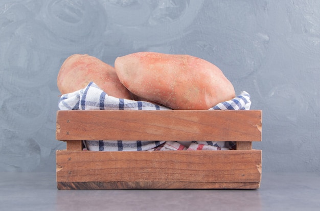 Pomme de terre sur la serviette dans la boîte sur la surface en marbre