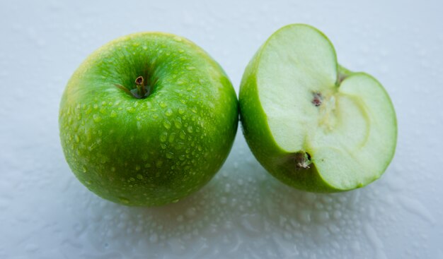 Pomme verte humide et moitié sur blanc. fermer.