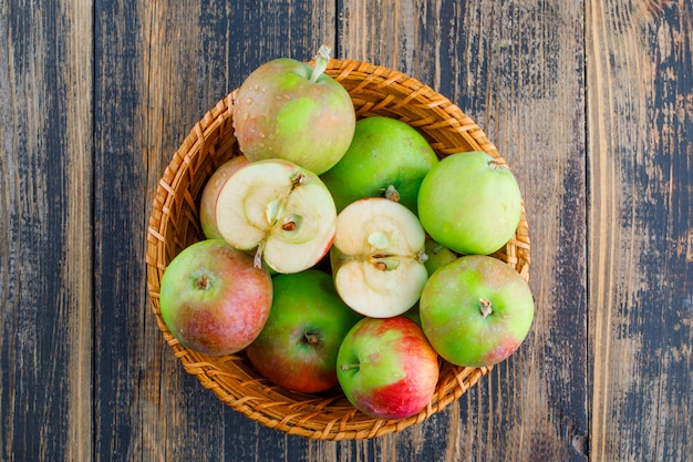 Pommes dans un panier en osier sur un fond en bois. pose à plat.