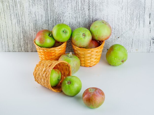 Pommes dans des paniers en osier sur blanc et grungy, high angle view.