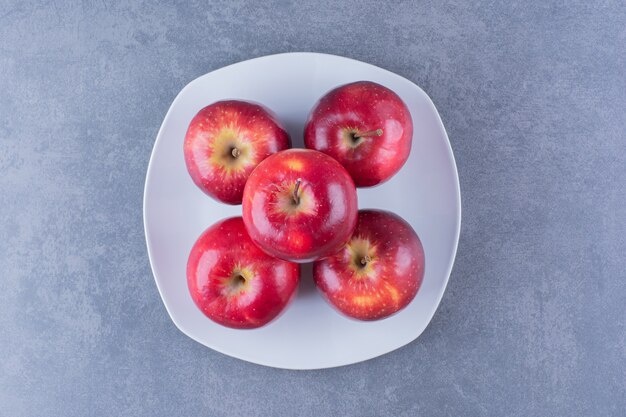 Pommes empilées les unes sur les autres sur une assiette, sur la surface sombre