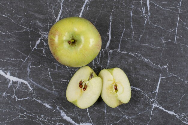 Pommes entières et tranchées sur marbre.