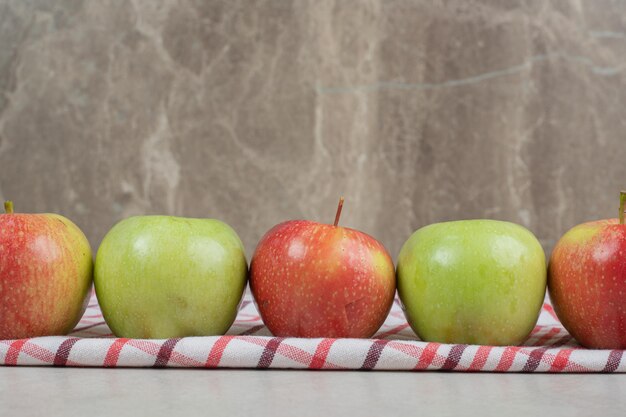 Pommes fraîches colorées sur nappe à rayures.