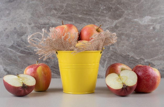 Photo gratuite pommes à l'intérieur et à côté d'un petit seau sur marbre