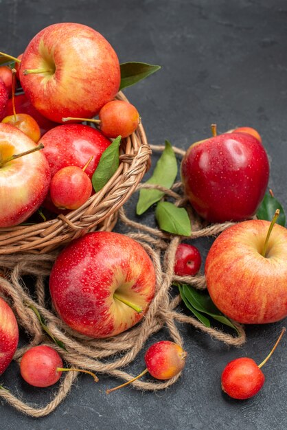 les pommes les pommes les cerises appétissantes sur la table sombre