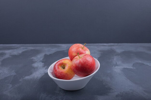 Pommes rouges fraîches dans un bol blanc.