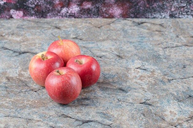 Pommes rouges isolées sur fond de marbre en béton.