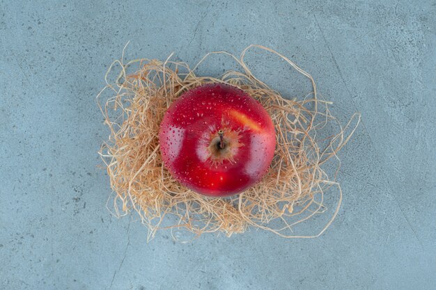 Pommes rouges sur paille sèche, sur fond de marbre. photo de haute qualité