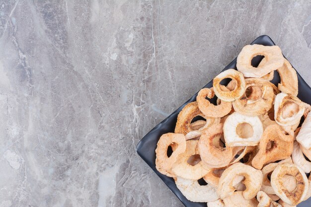 Pommes saines séchées sur assiette sombre.