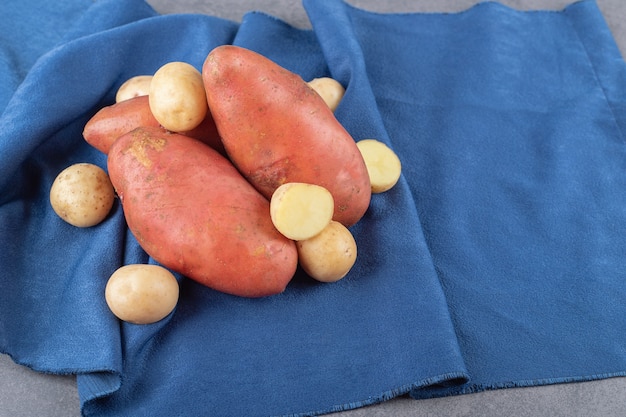 Pommes de terre crues à l'ail sur nappe bleue.