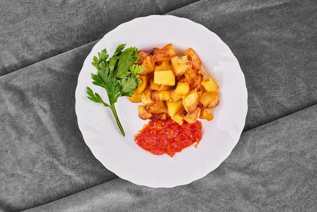 Pommes de terre frites avec de la pâte de tomates et des herbes.