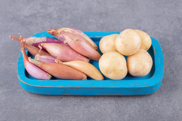 Pommes de terre non cuites à l'ail dans une planche de bois bleue.