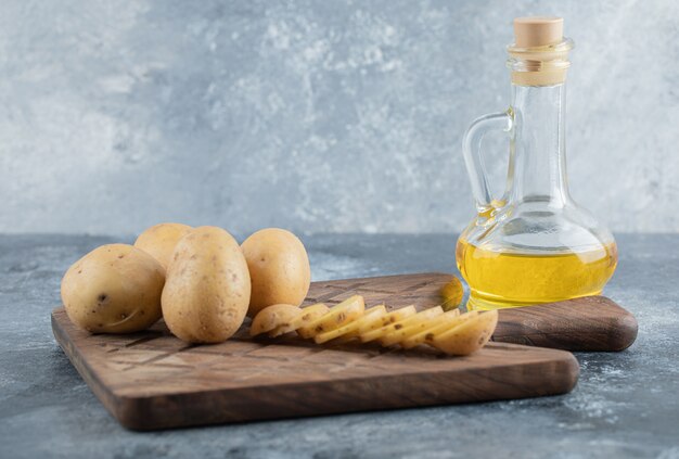 Pommes de terre en tranches et entières sur la planche à découper en bois. Photo de haute qualité