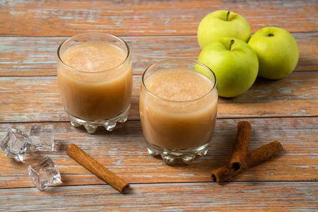 Pommes vertes, bâtons de cannelle et deux tasses de jus de fruits frais sur la table, vue du dessus