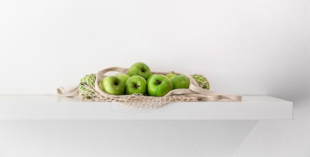 Pommes vertes dans un sac à cordes sur fond blanc