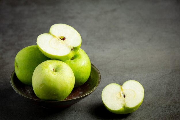 Pommes vertes fraîches coupées en deux mises dans un bol noir sur fond sombre