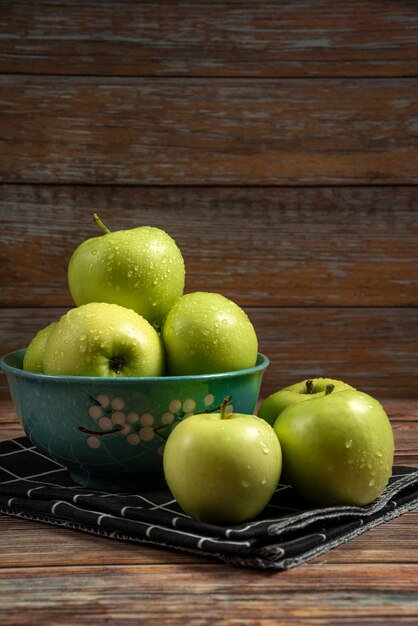 Pommes vertes fraîches avec des gouttes d'eau sur eux dans un bol bleu