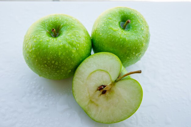 Pommes vertes humides et moitié sur blanc. fermer.