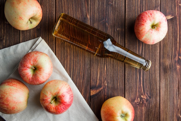 Pommes avec vue de dessus de jus sur un tissu et fond en bois