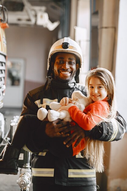 Pompier Arfican en uniforme. L'homme se prépare à travailler. Guy avec enfant.