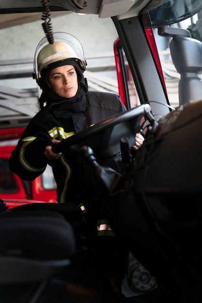 Pompier féminin à la station dans le camion de pompiers