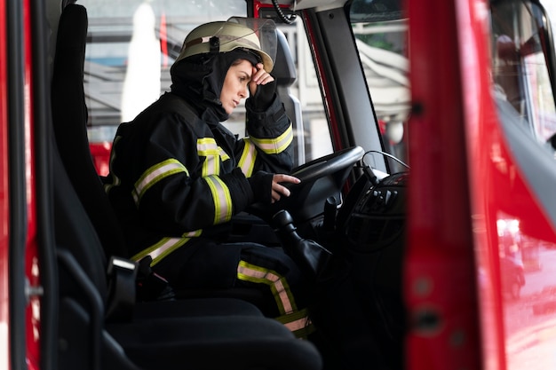 Pompier féminin à la station dans le camion de pompiers