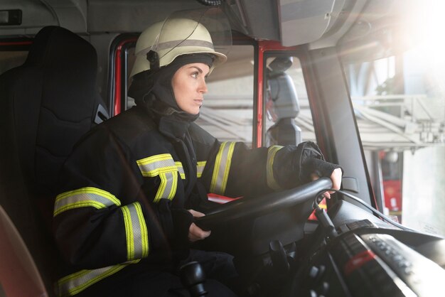 Pompier féminin à la station dans le camion de pompiers