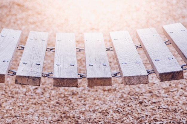 Un pont de chaîne en bois dans une aire de jeux, un fond de copeaux de bois floue.