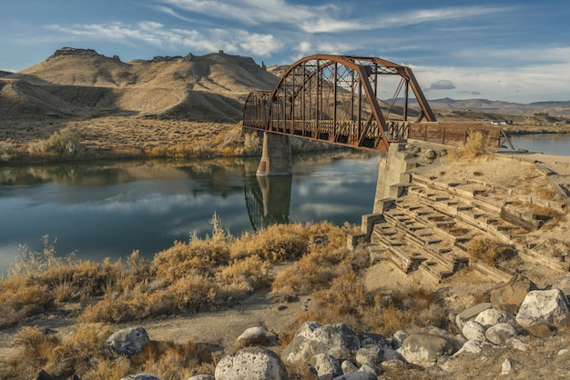 Pont sur la rivière au milieu des montagnes et du ciel bleu