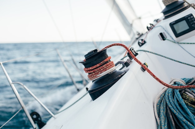 Pont d'un voilier professionnel ou d'un yacht de course pendant la compétition par une journée d'été ensoleillée et venteuse, se déplaçant rapidement dans les vagues et l'eau, avec spinnaker en place